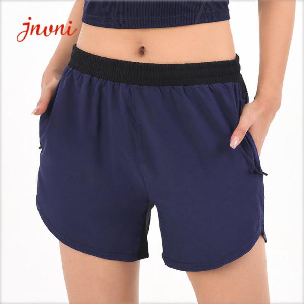 O short atlético das mulheres com os bolsos que correm bolsos laterais do short fraco do esporte