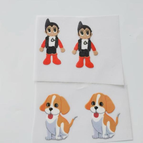 As imagens brilhantes dos desenhos animados do teste padrão passam etiquetas da transferência térmica do silicone para a roupa das crianças