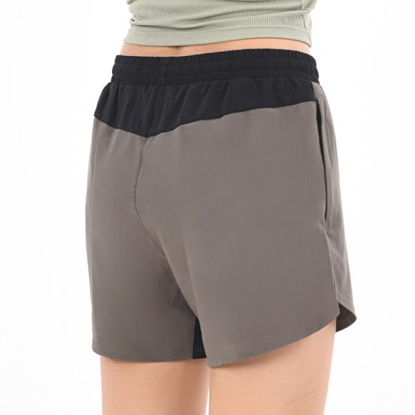 O short atlético das mulheres com os bolsos que correm bolsos laterais do short fraco do esporte