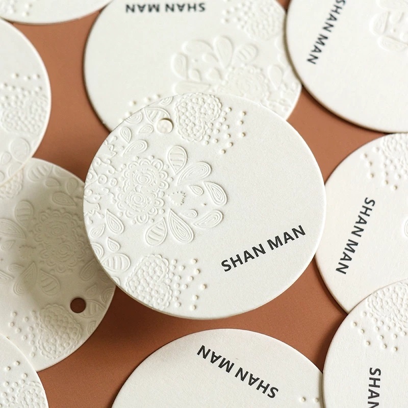 Embossed Round Paper Hang Tags With Relief Floral Pattern For Apparel Branding