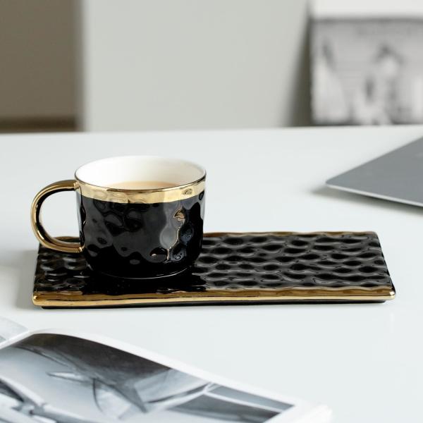 Elegantes tazas de cerámica negra con detalles dorados, texturas onduladas, para café, té y pastelería. Diseño moderno y minimalista.