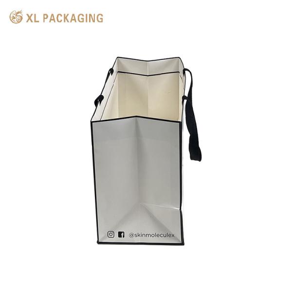 Custom branded luxury matte white coated art paper gift bag with wide black woven ribbon handle for cosmetic retail