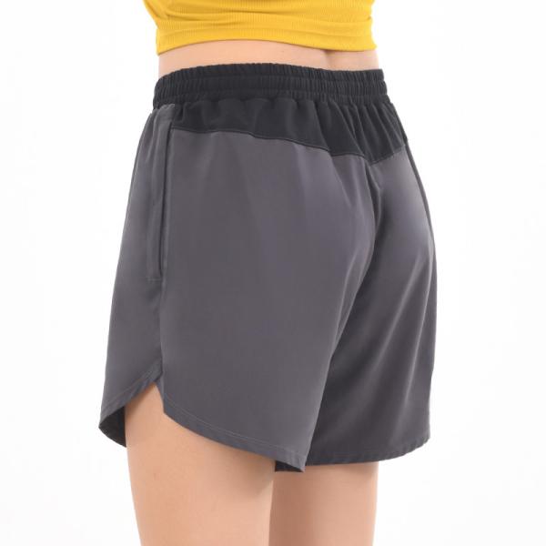 O short atlético das mulheres com os bolsos que correm bolsos laterais do short fraco do esporte