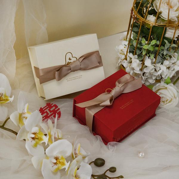 La boîte de mariage de luxe est équipée d'un emballage de cadeau élégant en crème rouge, un ruban satiné, un arc en or.