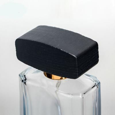 Empty glass perfume bottle with cap and pump spray collarwith wooden black cap