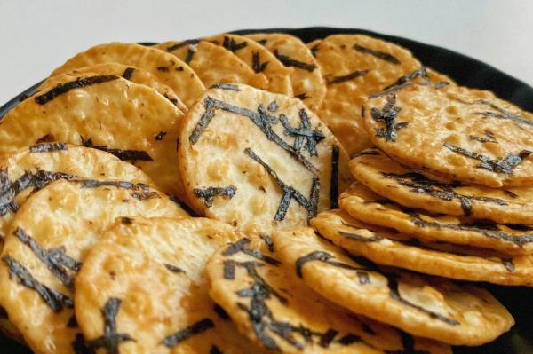Os petiscos japoneses dos biscoitos quentes da alga da venda em volta do arroz endurecem o petisco torrado da grão dos biscoitos do arroz