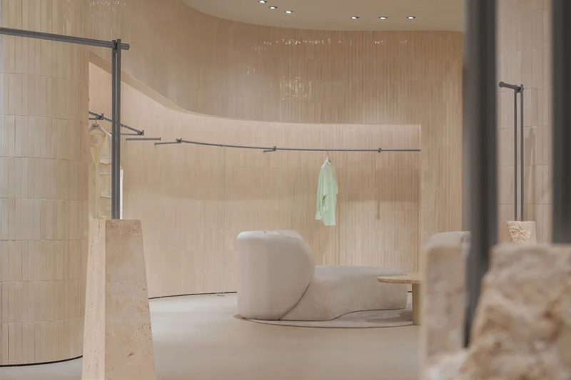 Wabi Sabi Minimalist Women Clothing Store Interior Design with Natural Travertine Curved Wall and Multi-functional Zoning Layout