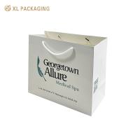 Logotipo de la empresa personalizado Bolsas de papel de compras Bolsas de papel recubiertas de alta calidad Bolsas de mano para ropa zapatos Embalaje minorista Manija resistente Laminado de mate brillante y descuentos para pedidos al por mayor