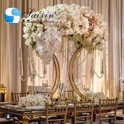 Saixin desenha a peça central da festa de casamento, o suporte de uma panela de flores de metal dourado.