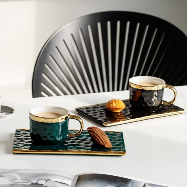 Elegantes tazas de cerámica negra con detalles dorados, texturas onduladas, para café, té y pastelería. Diseño moderno y minimalista.