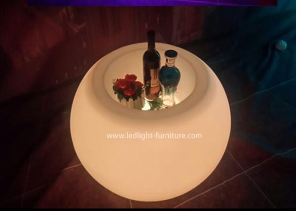 A bola dada forma conduzida ilumina acima a mesa de centro com cubeta de gelo e suporte de garrafa do vinho