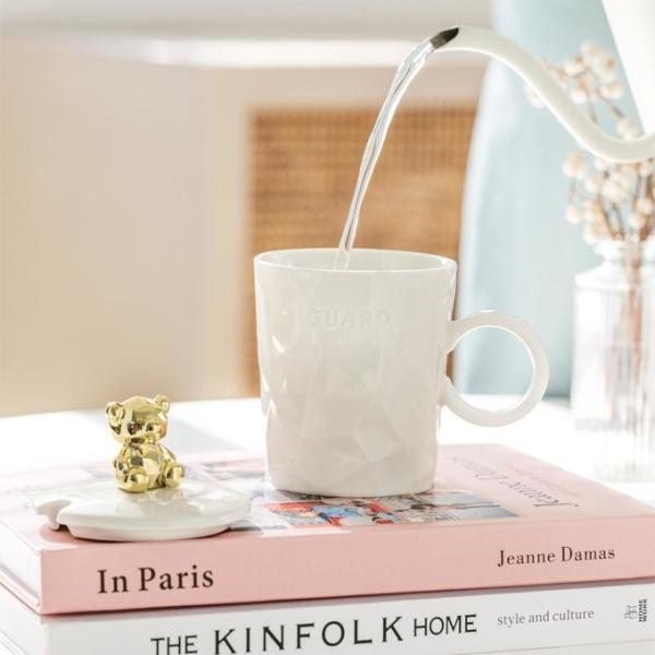 Une tasse en céramique haut de gamme avec un couvercle en or pour ours en peluche et une tasse en céramique pour filles