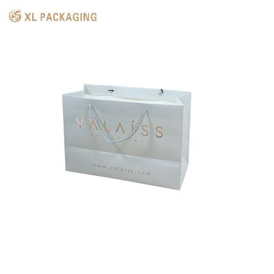 Sacs en papier d'art blanc rigide avec logo personnalisé Emballage de luxe pour achats avec poignées découpées Revêtement résistant aux rayures Conception facile à transporter Durable pour les cadeaux lourds Élégant pour les expériences de marque
