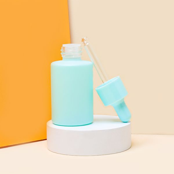 Os azul-céu colorem o conta-gotas de vidro do soro engarrafam o óleo de cabelo que empacota 30ml