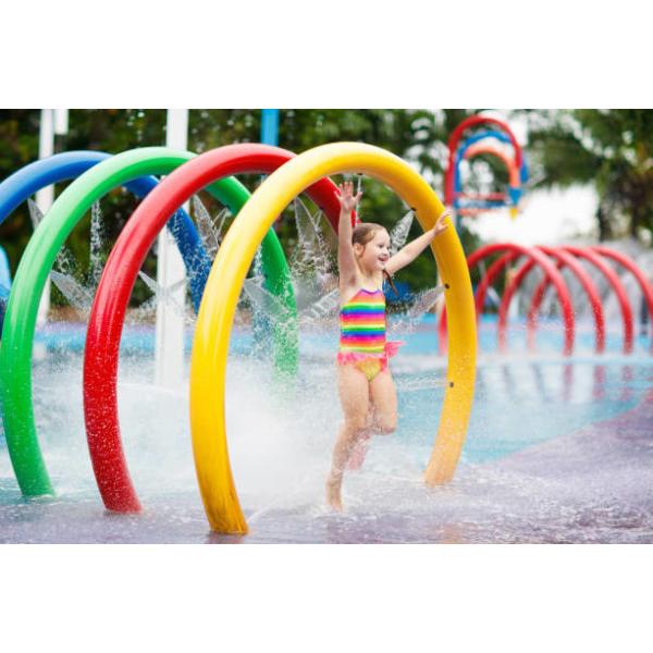 Los niños del círculo del arco iris del parque del espray de agua riegan el parque colorido del chapoteo del agua del patio