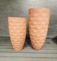 Jardinera redonda de fibra de arcilla con tono terracota cálido y terroso con baldosas redondeadas dispuestas