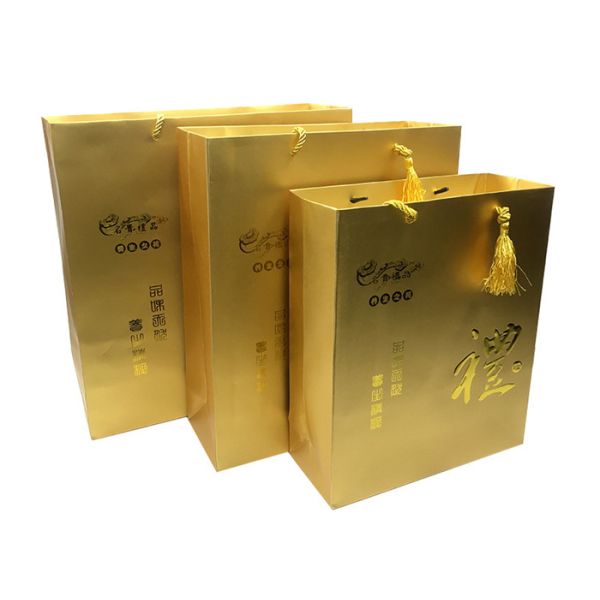 Изготовленный на заказ роскошный напечатанный подарок бумаги золота кладет в мешки с выбитыми ручками Tassel логотипа